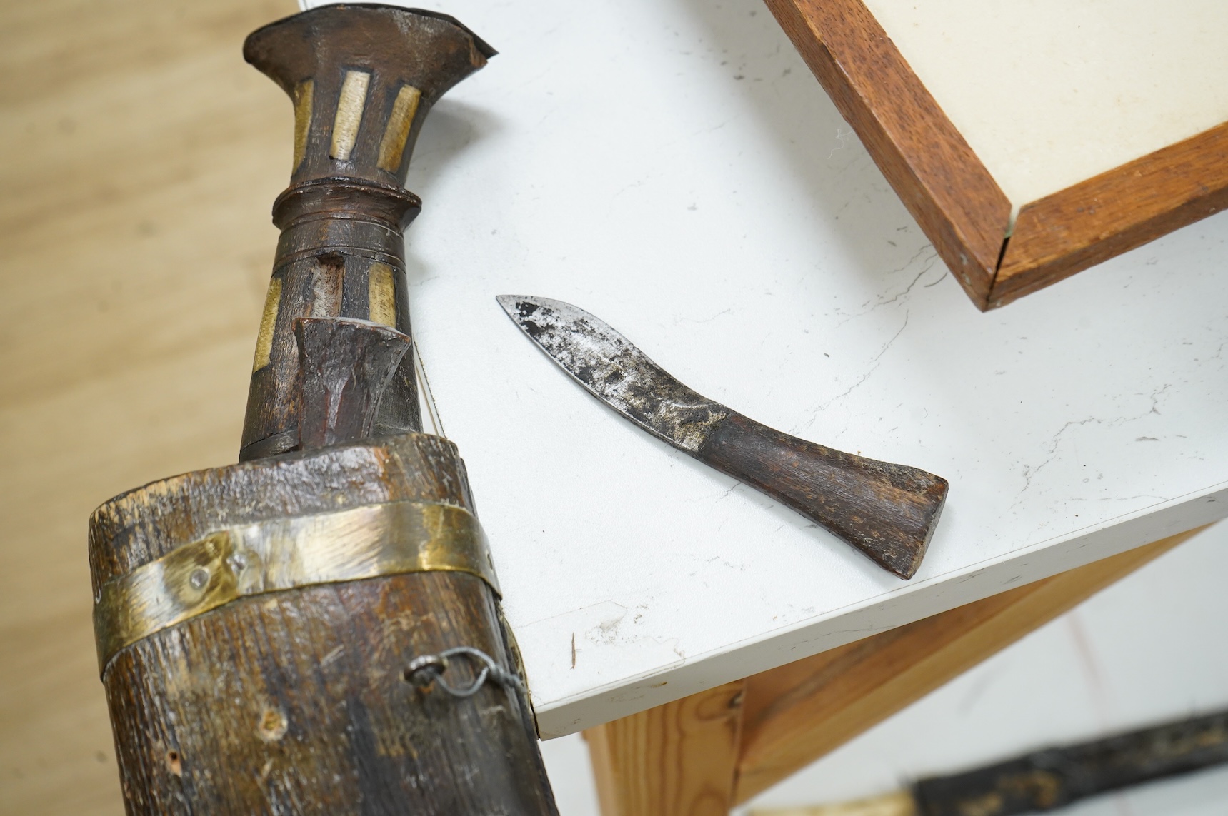 A decorative Indian axe, the large head inlaid with brass Hindu figures, together with a brass mounted North Indian kukri, another similar knife with bone handle, and a large shovel-shaped copper and brass item possibly